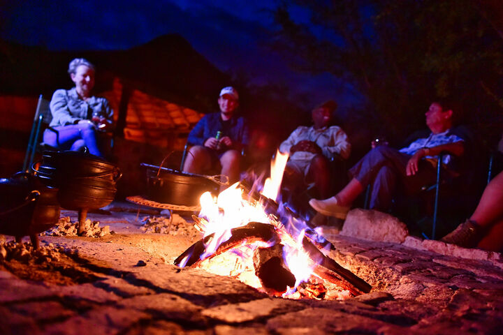 Visitors siting by a camp fire